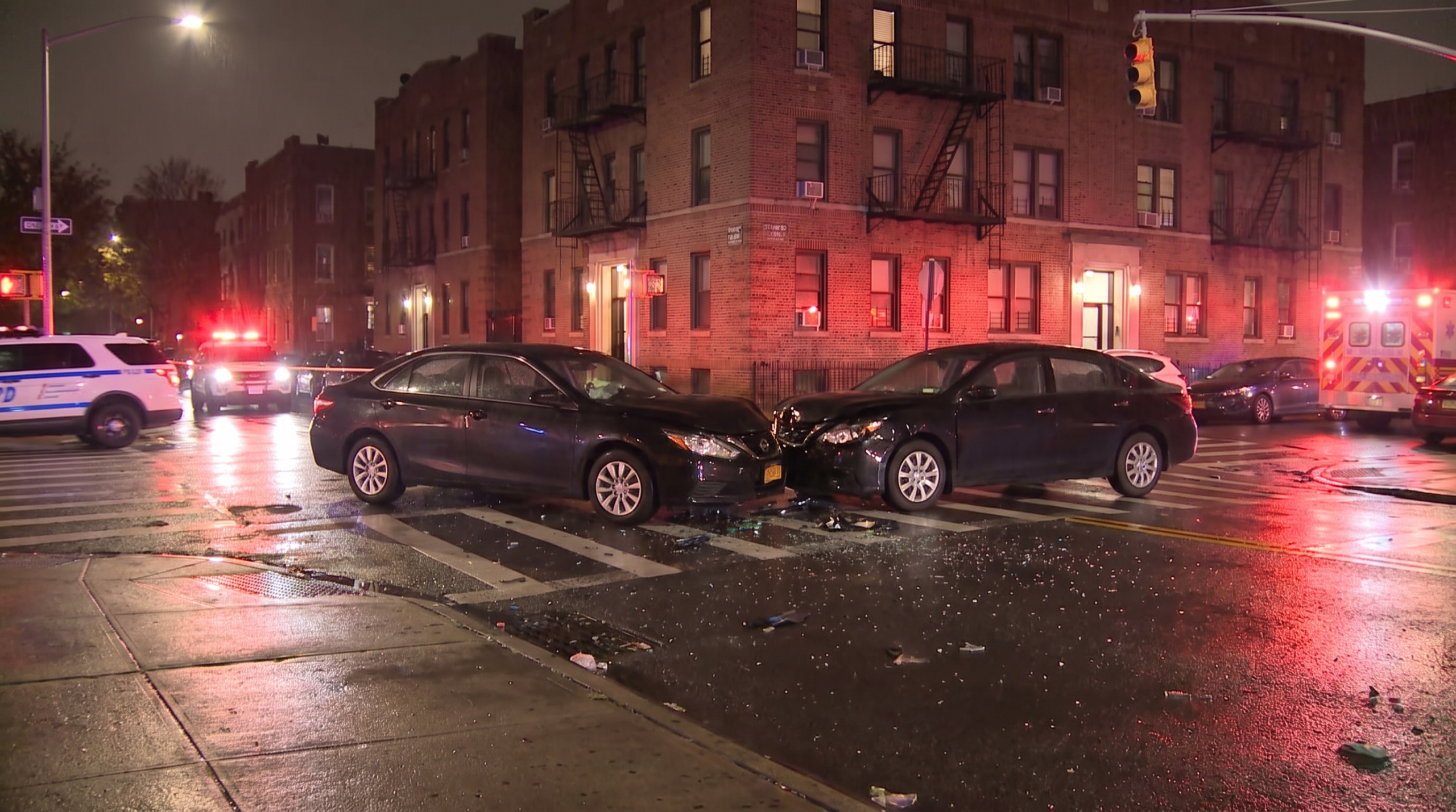 Nighttime Brooklyn intersection after a two-vehicle collision with emergency lights