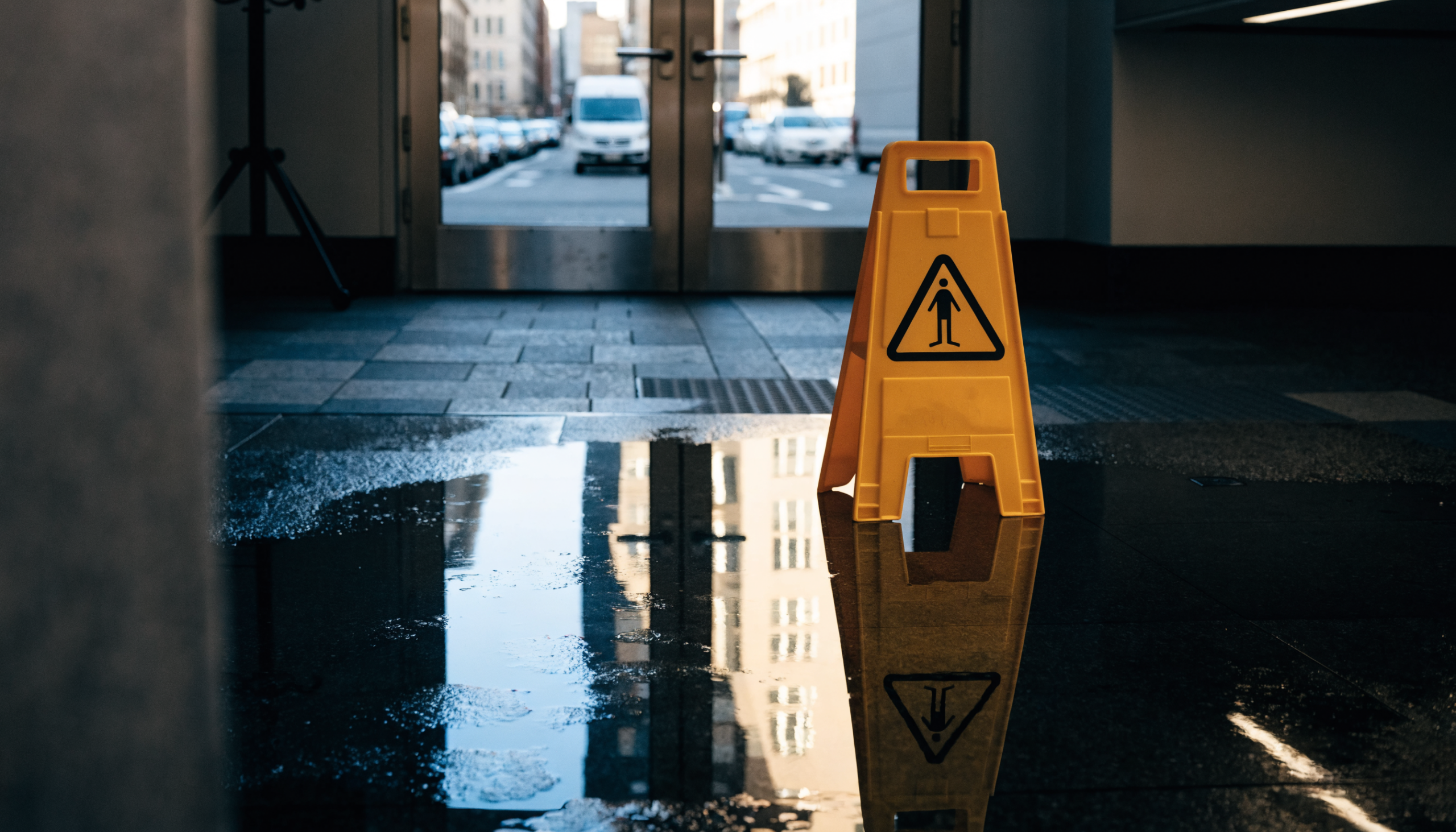 Yellow wet-floor caution sign on a wet New York City lobby floor, NYC slip and fall
